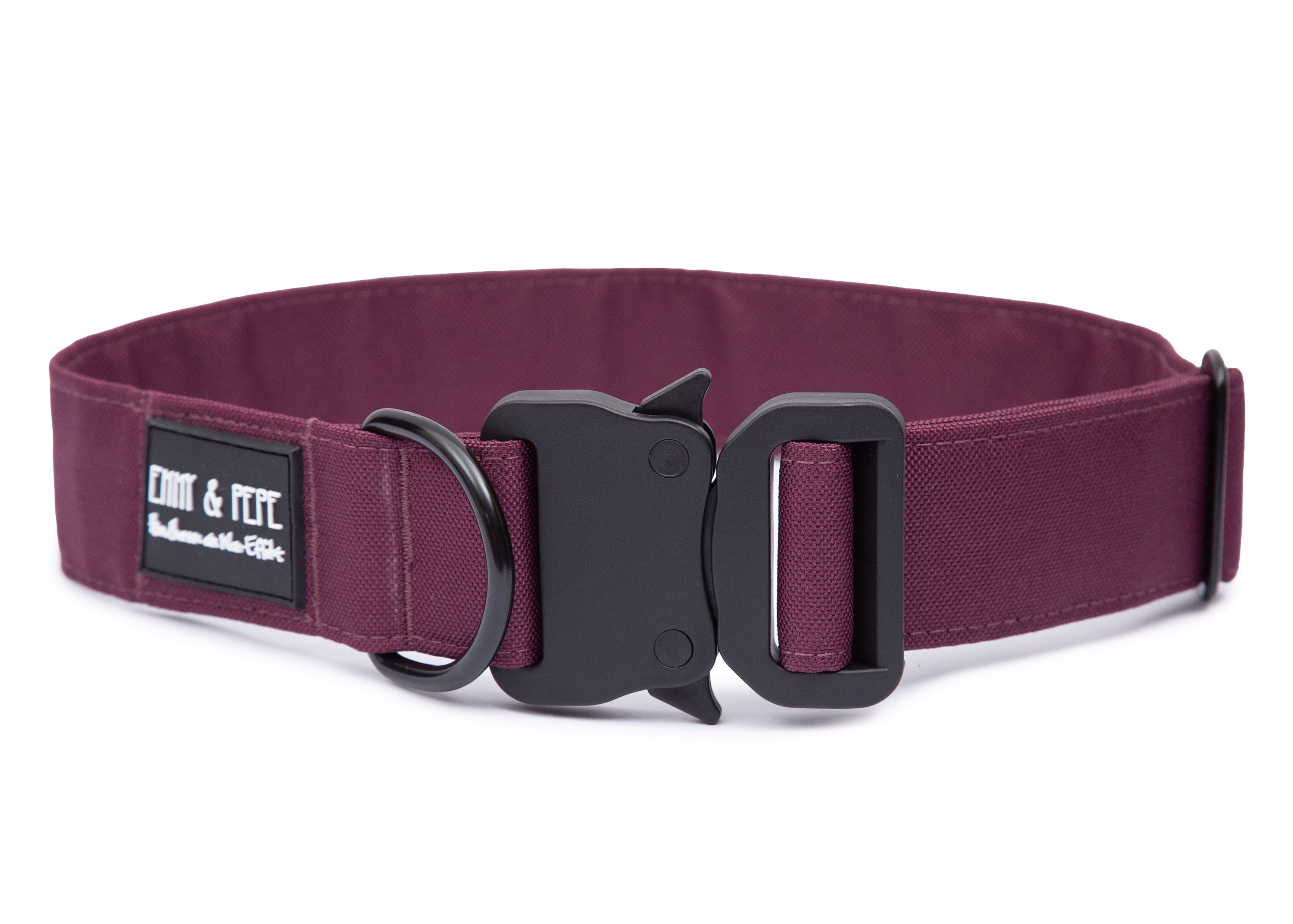 Weinrotes Hundehalsband aus Stoff mit schwarzem Kunststoff-Sicherheitsverschluss und schwarzem Metallring zur Befestigung einer Leine. Das Halsband ist vor weißem Hintergrund fotografiert und zeigt eine breite, verstellbare Ausführung mit gepolsterter Innenseite. Auf einem kleinen Etikett am Ring ist ein Markenlogo zu erkennen.