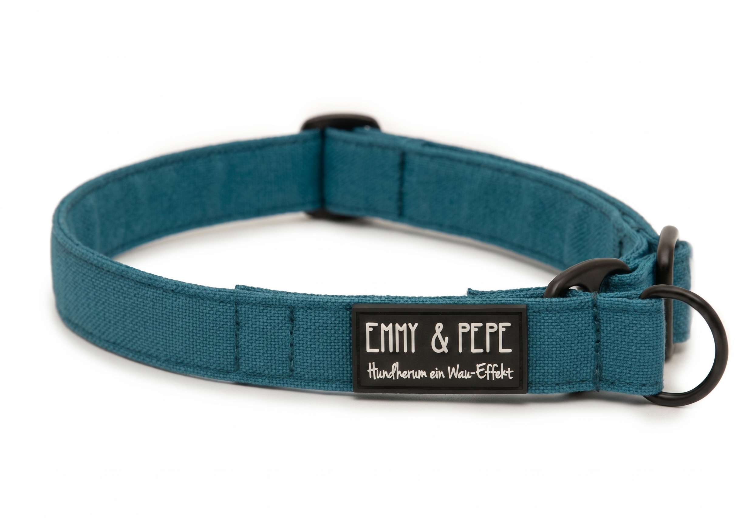 Nahaufnahme des türkisfarbenen Hundehalsbands mit schwarzer Hardware. Der Patch zeigt den vollständig Slogan „Hundherum ein Wau-Effekt“ in weißer Schreibschrift unter dem „EMMY & PEPE“ Markennamen.