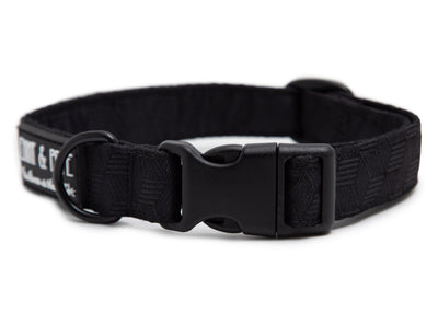 Schwarzes Hundehalsband. Das Halsband verfügt über eine robuste, schwarzer Steckschnalle mit „EMMY & PEPE“-Gravur sowie schwarzem Metallring. Freigestellte Produktaufnahme auf weißem Hintergrund.