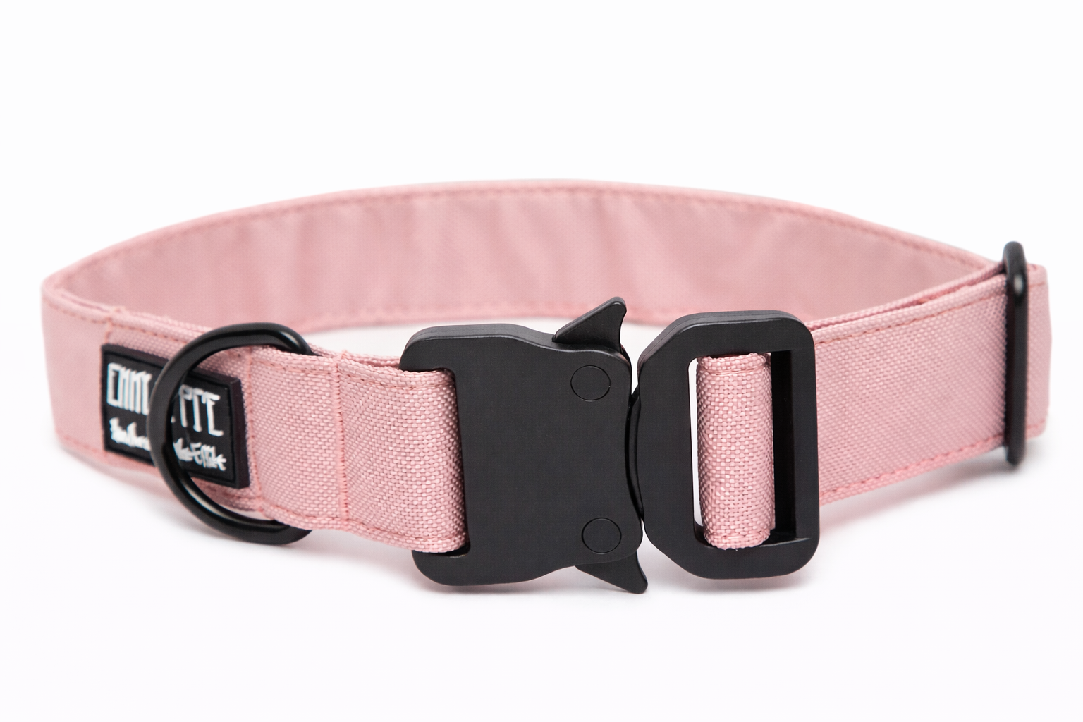 Rosanes Hundehalsband aus Stoff mit schwarzem Kunststoff-Sicherheitsverschluss und schwarzem Metallring zur Befestigung einer Leine. Das Halsband ist vor weißem Hintergrund fotografiert und zeigt eine breite, verstellbare Ausführung mit gepolsterter Innenseite. Auf einem kleinen Etikett am Ring ist ein Markenlogo zu erkennen.