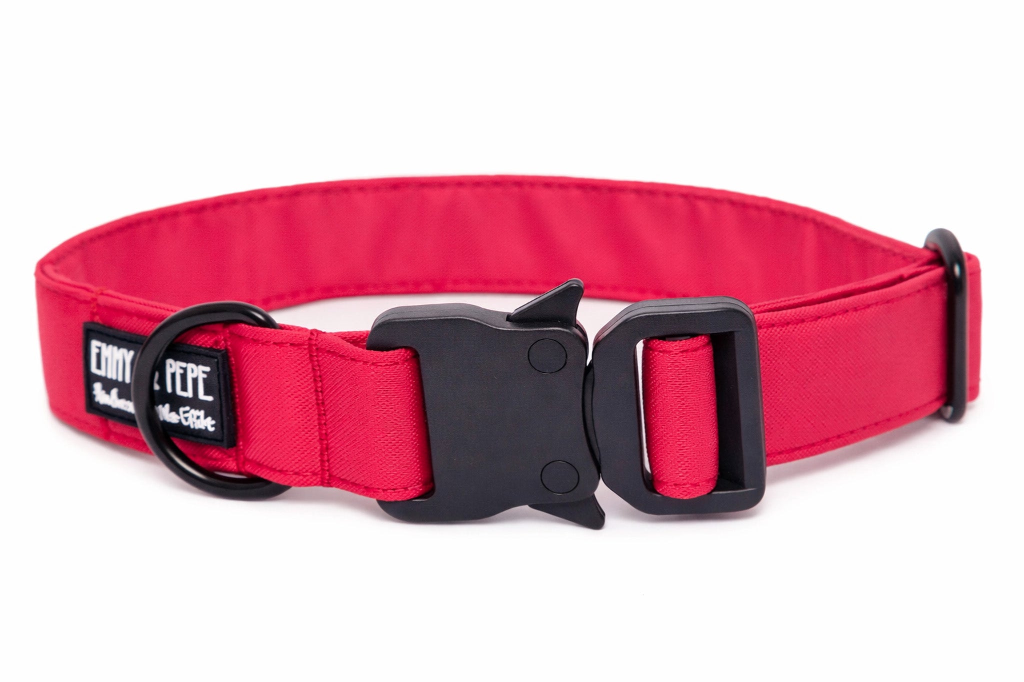 Neon Pinkes Hundehalsband aus Stoff mit schwarzem Kunststoff-Sicherheitsverschluss und schwarzem Metallring zur Befestigung einer Leine. Das Halsband ist vor weißem Hintergrund fotografiert und zeigt eine breite, verstellbare Ausführung mit gepolsterter Innenseite. Auf einem kleinen Etikett am Ring ist ein Markenlogo zu erkennen.