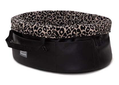  Wau-Snuggle Reisebett in oval mit robustem schwarzen Kunstleder an der Außenseite und einem weichen, beigen Innenfutter mit schwarzem Leopardenmuster 