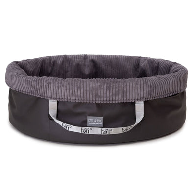 Freigestelltes ovales Wau-Snuggle Cord Dark Grey Hundekörbchen für unterwegs von EMMY & PEPE mit hohem Rand und dunkelgrauem Cordstoff innen.
