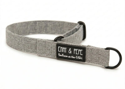 Graues Zugstopphalsband mit schwarzer Metallhardware und „EMMY & PEPE“-Label mit Schriftzug „Wau-Effekt“ auf weißem Hintergrund.